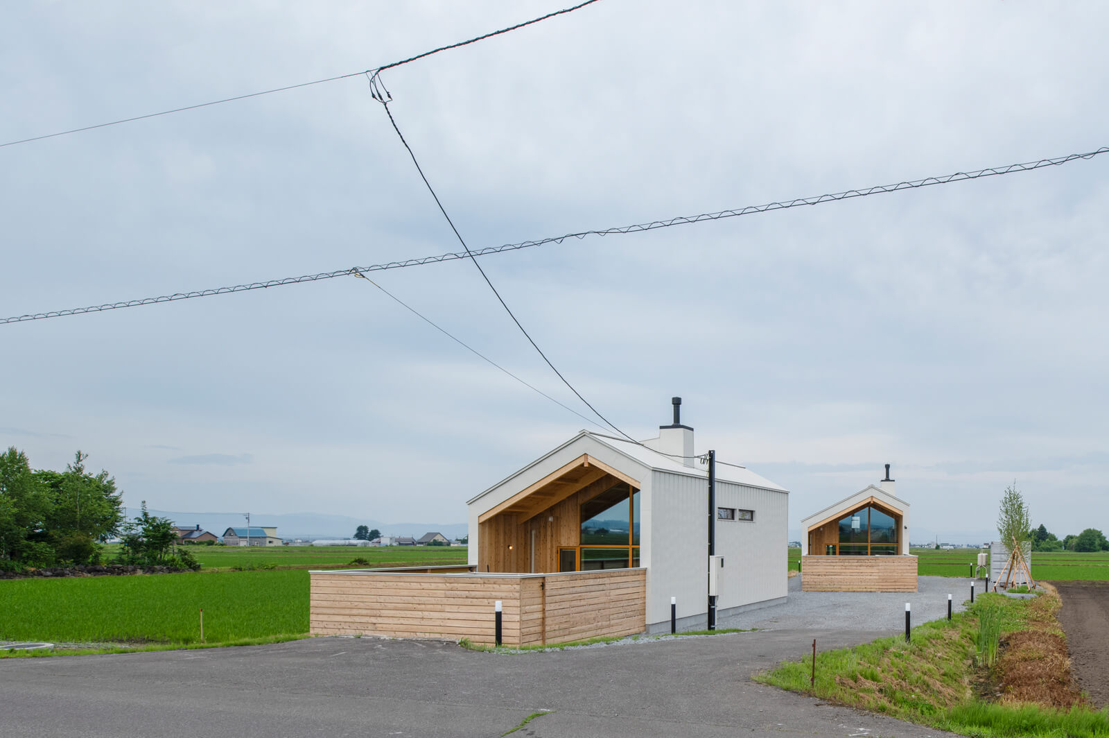 田園の中に佇む2棟のコテージ。奥のコテージは、山の稜線を望むために角度を振って配置した