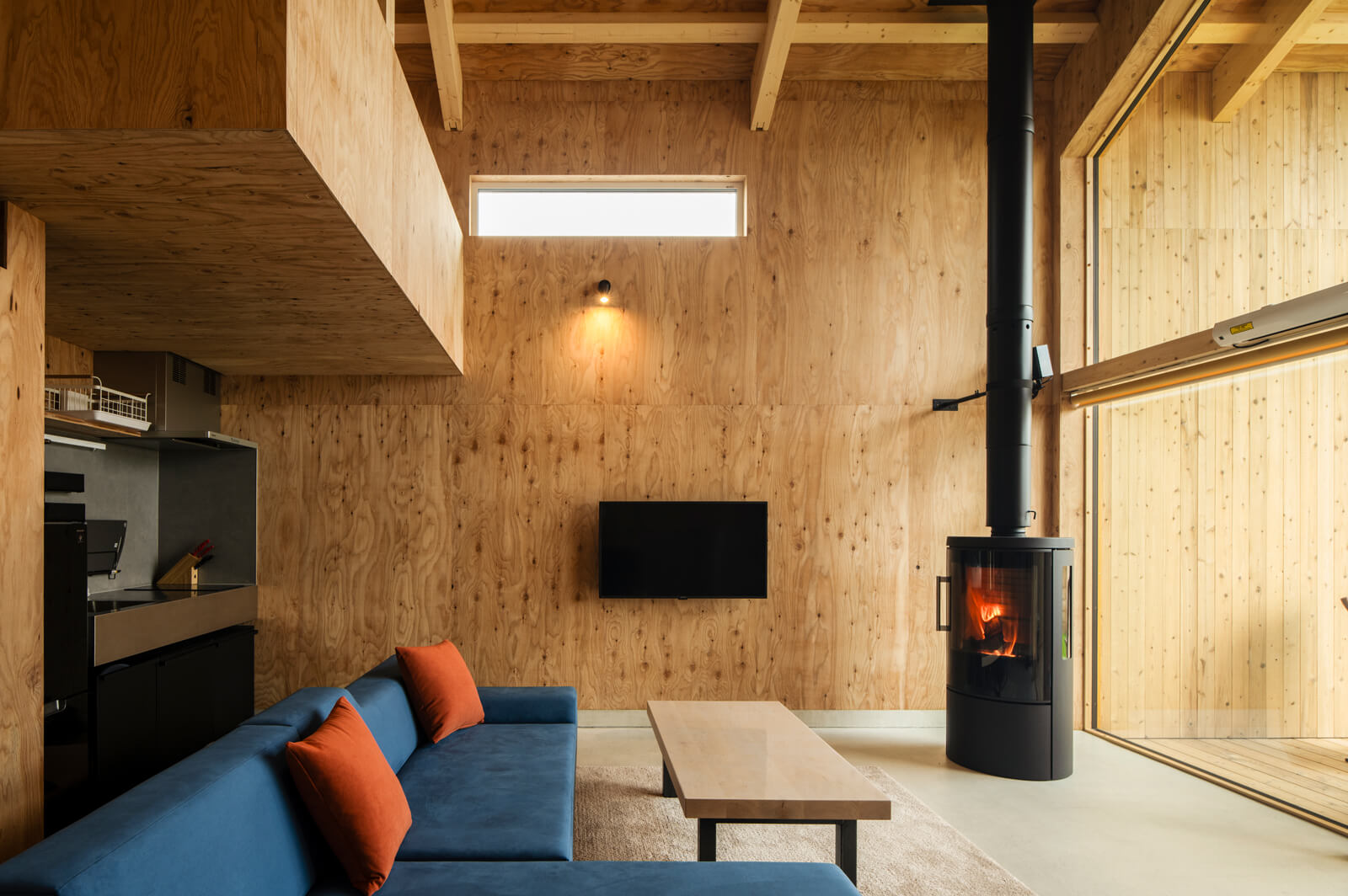 北側の壁は9㎜の針葉樹合板を張って仕上げた。ラフな素材感が薪ストーブによく似合う