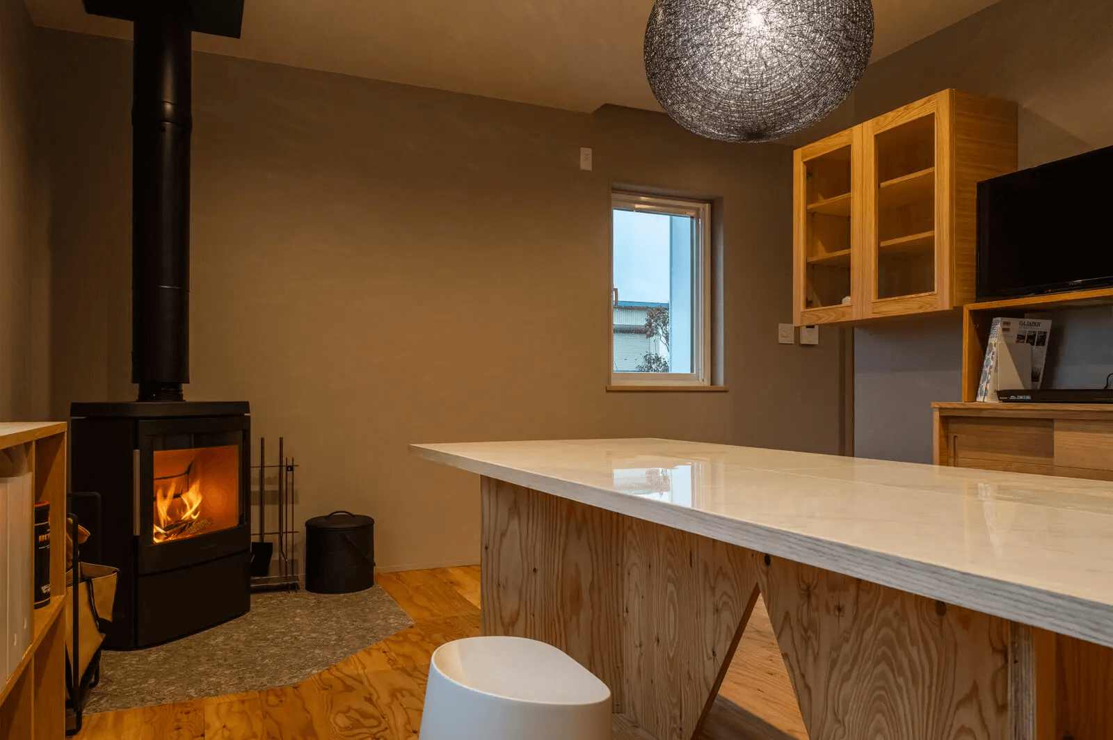 シンプルなインテリアでコーディネートされたダイニング・キッチンに、薪ストーブの炎が彩りを添える